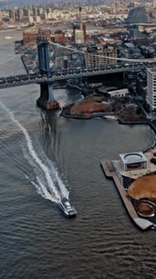 View of Brooklyn Bridge with boat cruising under Manhattan skyline