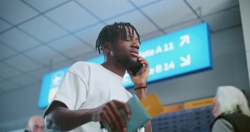 Airport Terminal Man Talking By Phone Checking Flight Information on Arrival and Departure Display