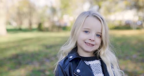 Portrait of blonde girl at park, smiling and looking at camera