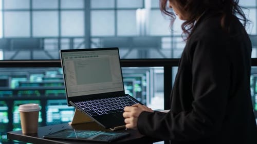 Technician Using Laptop in Data Center Finetuning Network Protocols