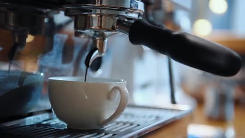 Close up view of white cup pouring by coffee on the special device in bar