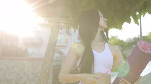 Sporty Woman Holding a Yoga Mat and Going for a Workout in the Park