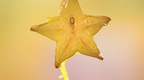 Makroaufnahme von fließendem Karambolensaft aus halbierter Karambola-Sternfrucht in Zeitlupe