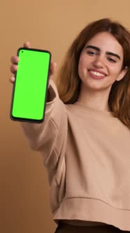 Woman Showing Cellphone with Green Screen in Studio Vertical Footage