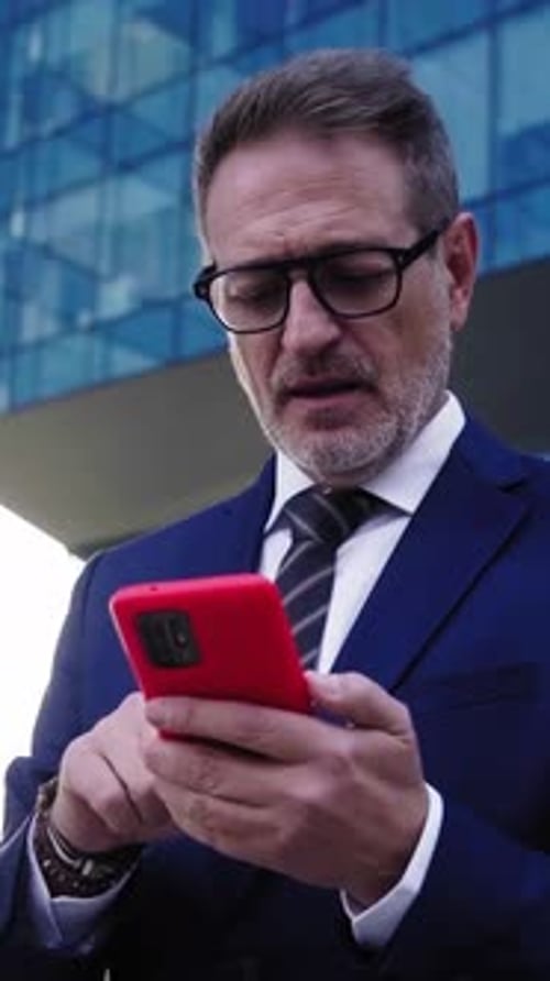 Man in Suit Using Red Mobile Phone