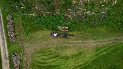 Drohne kippt auf Feldtraktor und Holzstapel, die nach der Abholzung der Bäume sauber abgeholzt wurden, Aufnahme zeigt su