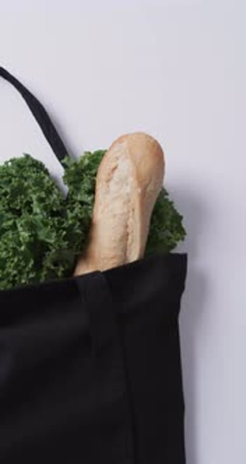 Vídeo vertical de bolsa de lona negra con perejil, col rizada y baguette, espacio para copiar sobre fondo blanco