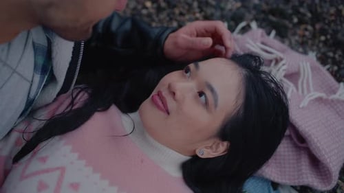 Loving Young Couple Lying on Beach Together