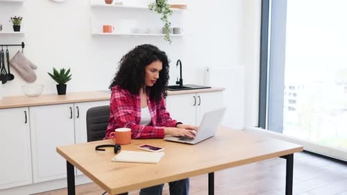 Woman Working on Laptop at Kitchen Table