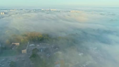 City seen above covered in fog, aerial drone view