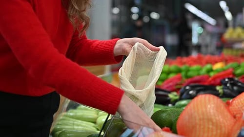 Mujer recogiendo aguacates en una bolsa reutilizable en una tienda. Temáticas del Día de la Tierra y la Ecología. Cámara lenta