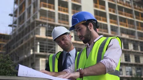Construction workers review plans at building site