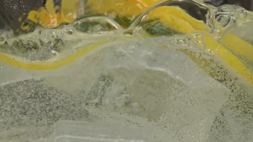 Pouring Sparkling Soda into Glass with Lemon and Ice