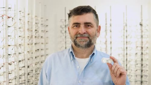 Hombre mayor sostiene lentes de contacto en las manos