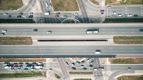 Overhead drone shot of traffic driving over roundabout with highway tunnel underneath, infrastructur