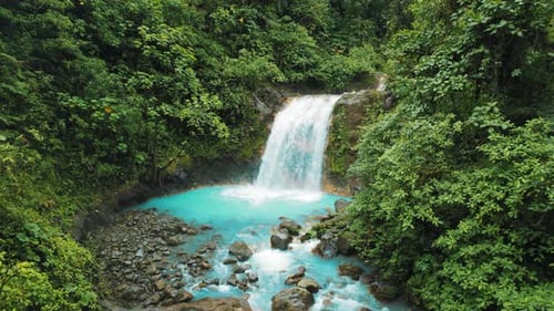 Close-up view of bright blue pool and waterfall in the rainforest of Costa Rica