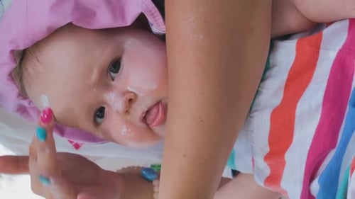 Mother Applying Sunscreen on Face of Baby