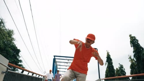 Young Man Dances with Friends on Urban Bridge