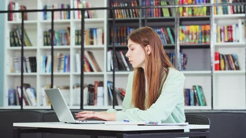 Young attractive university student studying at library