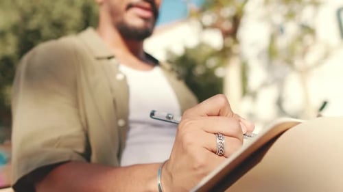 Close-up of the hand of young student writing with pen in notebook