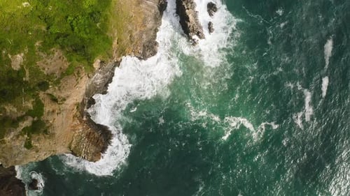 Bird's eye view over cliff's edge on Oregon Coast, battered by Pacific Ocean.