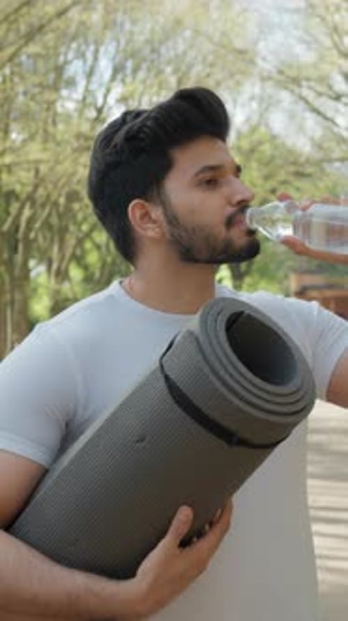 Vertical Screen Side View of Arabian Bearded Man Wearing Sport Clothes Drinking