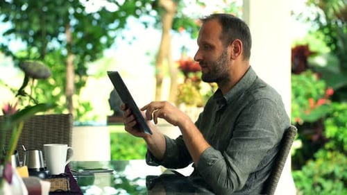 Young Man Using Tablet Computer Sitting in Garden 30s