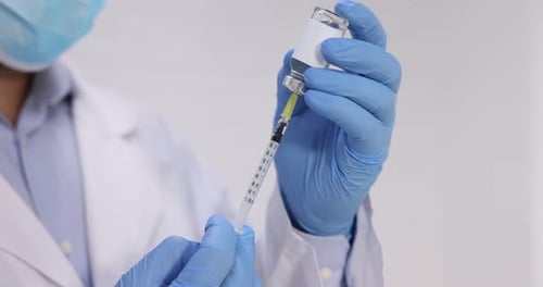 Vaccination. Medical worker filling syringe with medication indoors, closeup