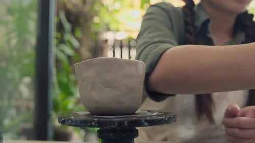 Woman Making Clay Pot Wet with Sponge in Workshop