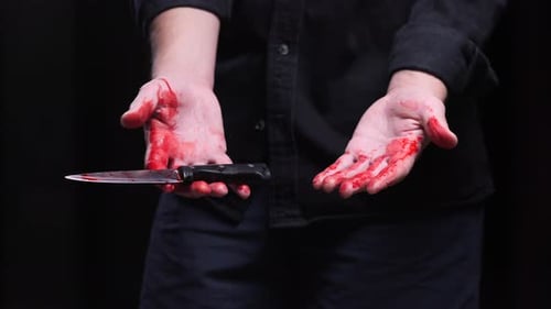 Asesino muestra manos ensangrentadas y dejando caer un cuchillo después de asesinar
