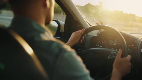Man Drives a Car Along the Road the Setting Sun Shines in the Windshield