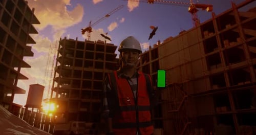 Asian Male Engineer Smiling And Showing Green Screen Smartphone At Construction Site