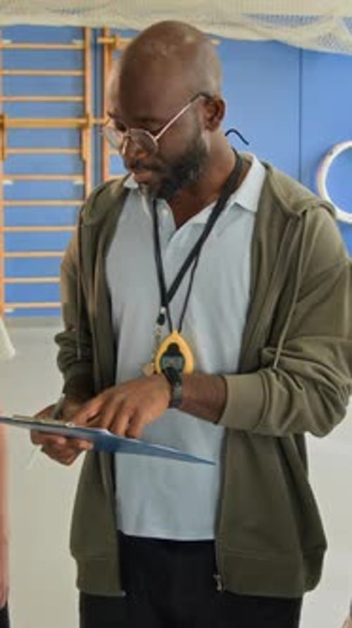 African American Man as Coach with Kids at Indoor Gym Vertical