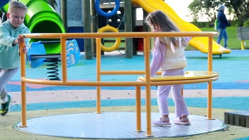 Joyful Children Spinning on a Playground Carousel in a Colorful Park Setting Childhood Moments