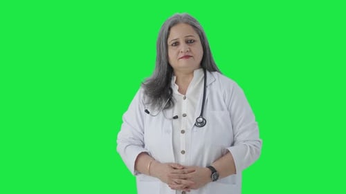 Indian senior female doctor looking Green screen