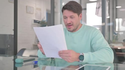Man Reading Documents at Office Desk