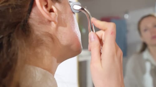 Woman Massaging Face with Metal Facial Roller