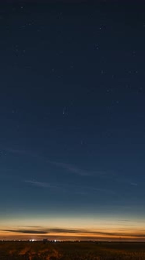 Starry Night Sky Over Field With City Lights