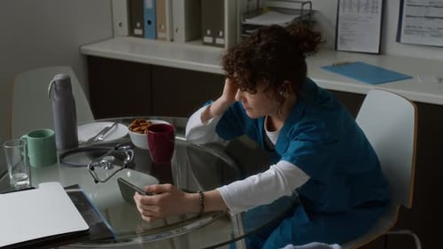 Weary Doctor Looking at Smartphone on Break