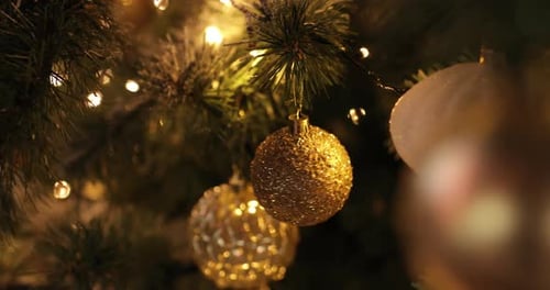 Close up a Christmas tree lights glittering at night. New Year fir tree with golden decorations,