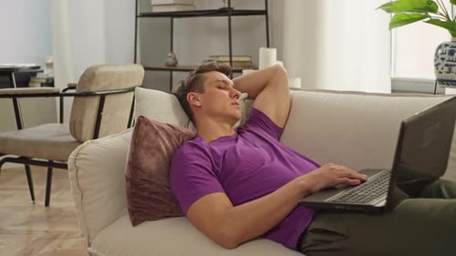 Young Adult Relaxing with Laptop on Couch