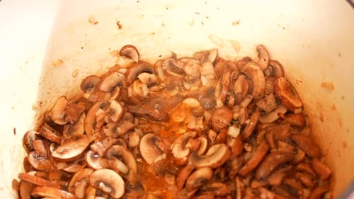 Sautéing mushrooms in an enamel Dutch oven pot - mushrooms frying and bubbling on the stove - close