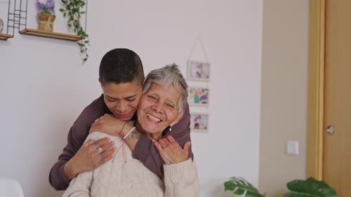 Loving Young Woman Embracing Smiling Senior Woman Indoors