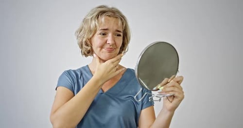 Woman Examining Skin in Handheld Mirror