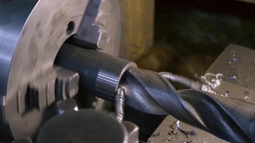 Drilling detail on lathe with metal shavings.