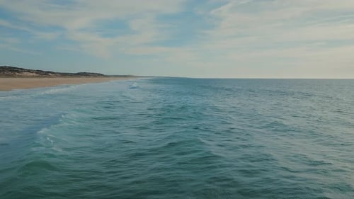Blue ocean waves moving towards the coastline on a sunny summer day.