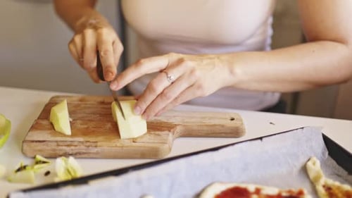 Frau schneidet grüne Äpfel auf Holzschneidebrett