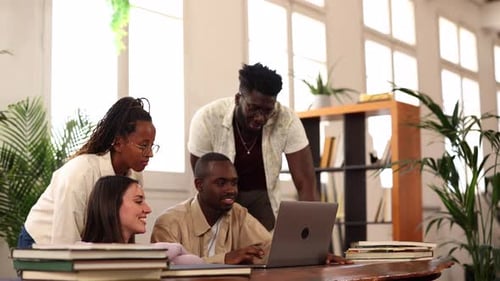 Students collaborating on laptop in library setting