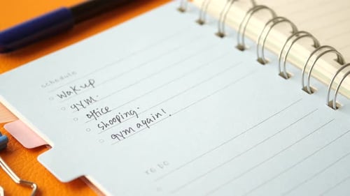 Writing on a Daily Planner on Table