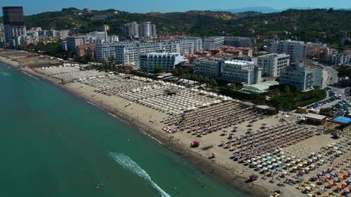 Large sandy beach on the Adriatic coast with beach umbrellas and sunbeds lined up in front of hotels